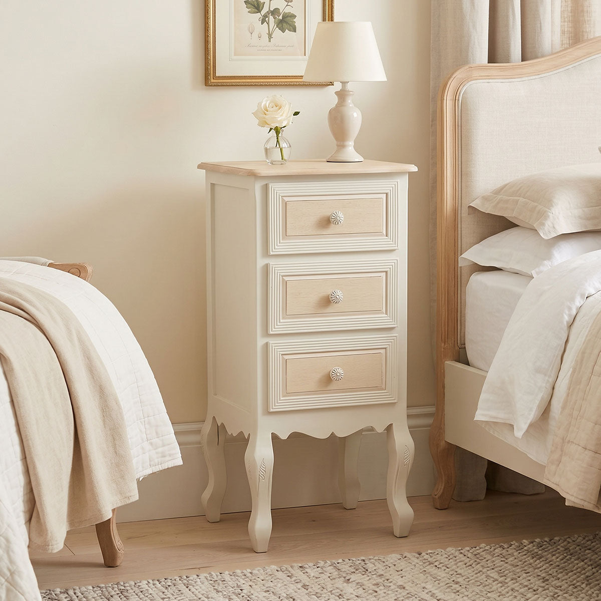 Префинета и издолжена ноќна масичка Bedside table Halin со горна плоча во природна нијанса на дрво, античко бела рамка, практична фиока и долна решеткаста полица